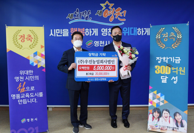 최기문 영천시장학회 이사장이 장학기금 300억원 달성의 주인공인 우진농업회사법인 최진욱 대표로부터 500만원의 장학금을 전달받고 있다. 영천시 제공