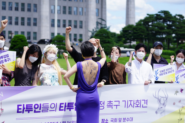 정의당 류호정 의원(뒷모습)이 국회에서 타투인들과 함께 타투입법 제정 촉구 기자회견을 하고 있다. 류 의원은 유명 타투이스트 밤이 그린 타투스티커를 등에 붙인 채 기자회견을 진행했다. 연합뉴스