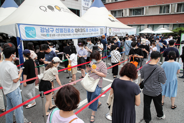 신종 코로나 바이러스감염증(코로나19) 신규 확진자가 1,212명을 기록한 7일 오후 무더위 속 서울 강남구 강남구보건소에 설치된 선별검사소를 찾은 시민들이 검사를 받기 위해 긴 줄을 서 있다. 이날 서울 강남과 송파 일대 선별진료소는 확진자 급증과 무역센터 현대백화점 집단 감염 여파로 종일 북새통을 이뤘다. 연합뉴스