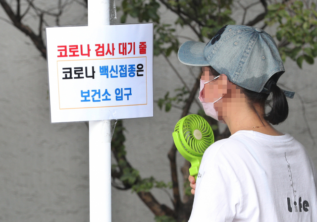 장마철 찜통더위가 기승을 부린 12일 오후 대구 수성구보건소 코로나19 선별진료소에서 한 시민이 휴대용선풍기로 더위를 식히며 순서를 기다리고 있다. 성일권 기자 sungig@imaeil.com