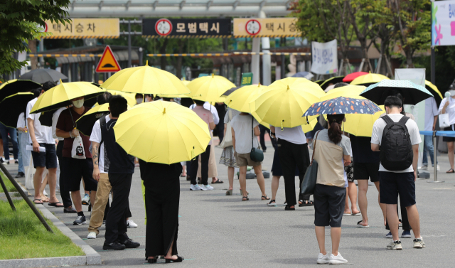 국내 신종 코로나바이러스감염증(코로나19) 신규 확진자 수가 역대 최다를 기록한 14일 오후 서울 서초구 고속버스터미널 광장에 마련된 임시선별검사소 앞에서 서초구가 마련한 양산을 빌려 쓴 시민들이 검사 순서를 기다리고 있다. 중앙방역대책본부에 따르면 이날 0시 기준 신규 확진자 수는 지난해 1월 20일 국내에서 첫 코로나19 환자가 발생한 이후 가장 많은 1천615명을 기록했다. 연합뉴스