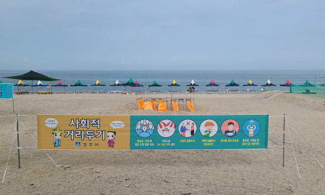 16일 개장한 경주 오류고아라해수욕장 백사장에 방역수칙을 안내하는 현수막이 걸려 있다. 멀리 그늘막 시설도 2m 간격을 두고 설치돼 있다. 김도훈 기자