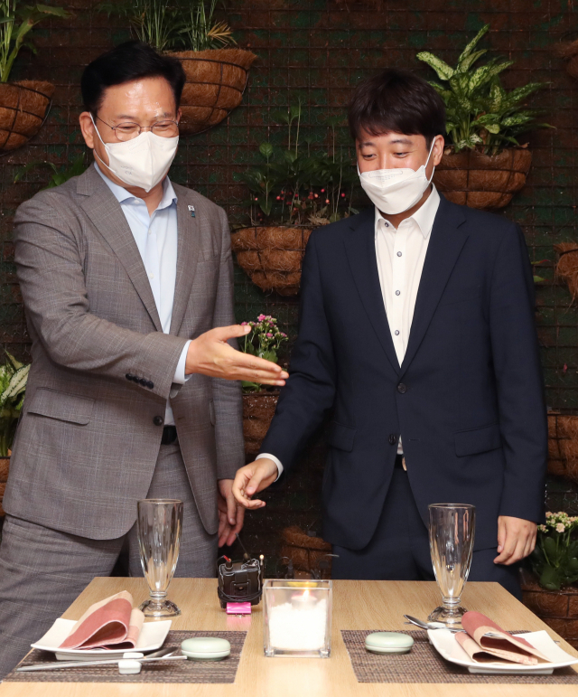 더불어민주당 송영길 대표(왼쪽)와 국민의힘 이준석 대표가 12일 서울 여의도의 한 식당에서 열린 만찬 회동에서 자리에 앉고 있다. 연합뉴스