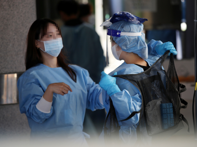 낮 기온이 35도 안팎에 이르는 무더위가 이어질 것으로 예보된 21일 오전 서울 동작구보건소 앞에 마련된 선별진료소에서 한 의료진이 아이스팩이 담긴 조끼를 입고 있다. 이날 신규 확진자 수는 1천700명대 후반까지 치솟으며 1주일 만에 또 최다 기록을 갈아치웠다. 연합뉴스