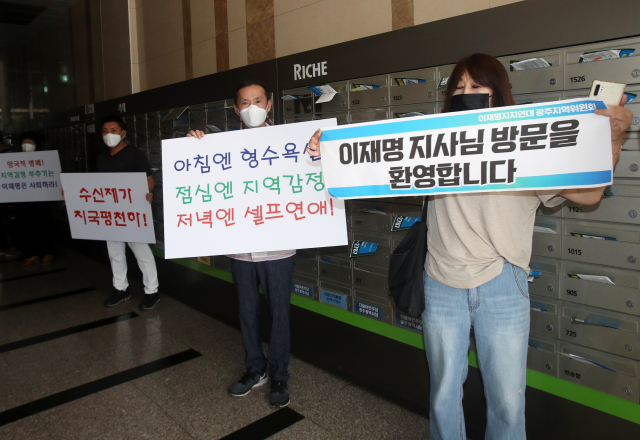 25일 광주 서구 치평동 더불어민주당 광주광역시당에서 기자간담회를 하는 더불어민주당 대선 예비후보인 이재명 경기도지사의 지지자와 반대하는 시민이 손팻말을 들고 있다. 연합뉴스