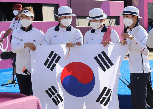 25일 일본 도쿄 유메노시마 공원 양궁장에서 열린 양궁 여자단체전 결승전에서 승리한 대한민국 여자양궁 대표팀이 류수정 감독과 태극기를 들고 포즈를 취하고 있다. 연합뉴스