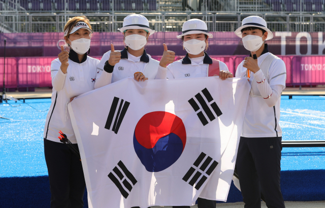 25일 일본 도쿄 유메노시마 공원 양궁장에서 열린 양궁 여자단체전 결승전에서 류수정 감독과 장민희, 강채영, 안산이 금메달을 확정지은 뒤 류수정 감독과 태극기를 들고 엄지손가락을 들어 보이고 있다. 연합뉴스