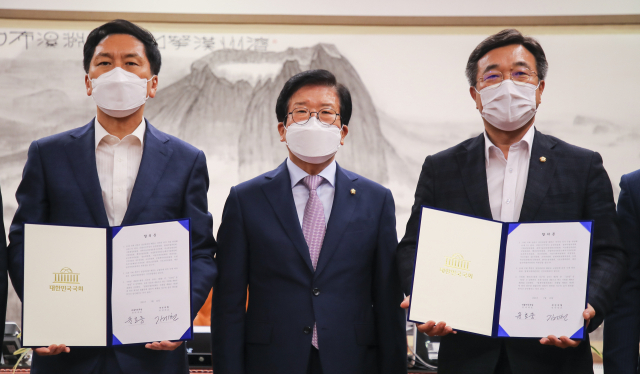 박병석 국회의장(가운데)과 더불어민주당 윤호중 원내대표(오른쪽), 국민의힘 김기현 원내대표(왼쪽)가 23일 오후 국회 의장실에서 추경안과 상임위원장 배분 등에 합의한 후 합의문을 들어보이고 있다. 연합뉴스