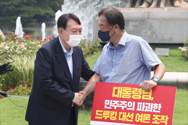 윤석열 대선 예비후보가 29일 오전 서울 종로구 청와대 앞 분수대 광장에서 드루킹 댓글 조작 사건과 관련해 문재인 대통령의 사과를 촉구하며 1인 시위를 하고 있는 국민의힘 정진석 의원을 방문해 악수하고 있다. 연합뉴스