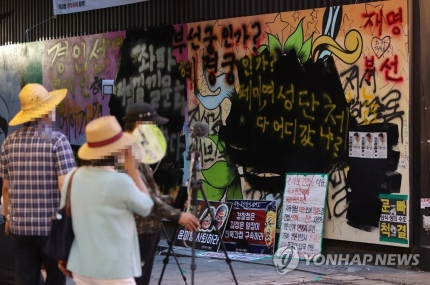 31일 서울 종로구 관철동의 한 중고서점 앞에 그려진 쥴리벽화를 한 유튜버가 검정색으로 덧칠했다. 연합뉴스