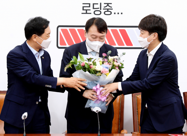 국민의힘에 입당한 윤석열 대선 예비후보가 2일 오전 서울 여의도 국회에서 이준석 당 대표(오른쪽)와 김기현 원내대표로부터 환영의 꽃다발을 받고 있다. 연합뉴스