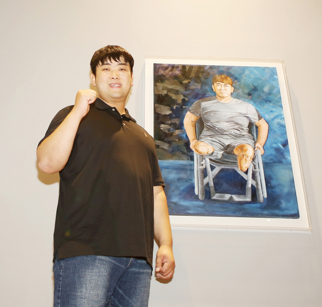 의족을 하고 일어선 하재헌 예비역 중사가 칠곡호국평화기념관에 전시된 자신의 그림 앞에서 파이팅을 외치고 있다. 칠곡군 제공
