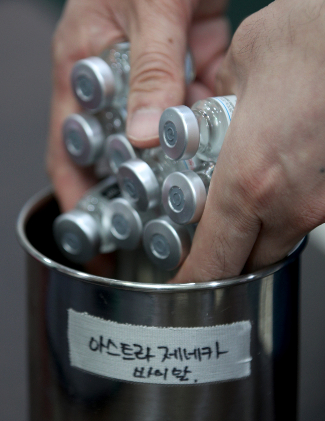 18일 대구 시내의 한 병원에서 의료진이 코로나19 백신 접종을 완료한 아스트라제네카(AZ) 공병을 버리고 있다. 대한의사협회 코로나19 대책 전문위원회는 정부가 AZ 백신 접종 연령을 잔여 백신에 한해 