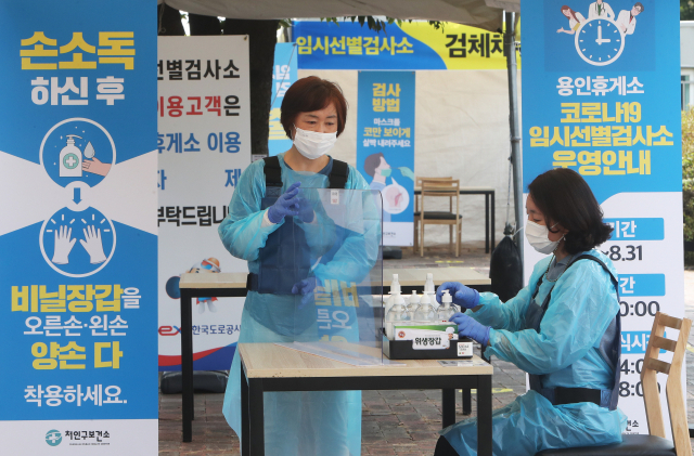 지난 12일 경기도 용인시 영동고속도로 용인휴게소 인천방향에 설치된 임시선별검사소에서 처인구보건소 관계자들이 운영을 하루 앞두고 준비작업을 하고 있다.연합뉴스