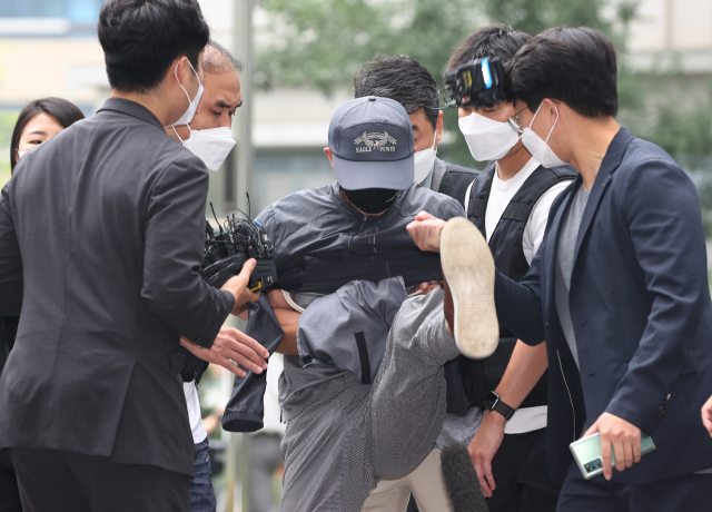 위치추적 전자장치(전자발찌) 훼손 전후로 여성 2명을 잇달아 살해한 혐의를 받는 강모가 31일 서울동부지법에서 열리는 영장실질심사에 출석하던 중 질문을 하려는 취재진의 마이크를 발로 걷어차고 있다. 연합뉴스