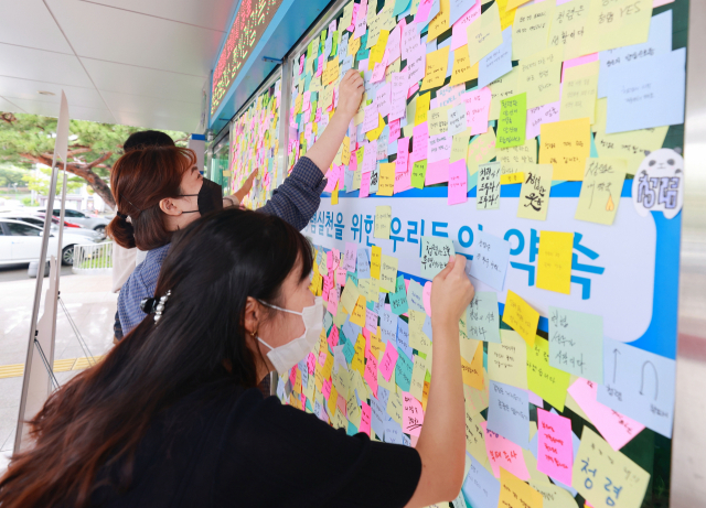 성주군 공무원들이 청렴 실천 의지를 적은 스티커를 성주군청 현관 청렴 실천 약속판에 붙이고 있다. 이영욱 기자
