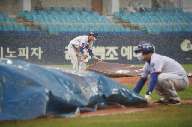 1일 대구삼성라이온즈파크에서 열린 삼성라이온즈와 키움히어로즈의 더블헤더 1차전 경기. 갑작스러운 폭우로 경기가 중단된 가운데 관계자들이 그라운드에 방수천을 덮고 있다. 1차전은 삼성이 7대1 강우 콜드승을 했고 2차전은 취소됐다. 연합뉴스