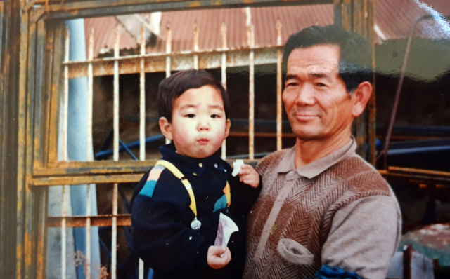 할아버지 박재오 씨가 1993년 경남 창녕군 유어면 작업실 앞에서 설날 만난 손자 박신영을 안고 찍은 기념사진. 가족제공.
