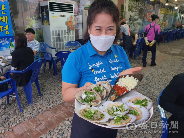 '한계령조개구이 본점'의 이명희(59) 사장이 조개구이 모듬한상을 들어보이며 푸짐한 양을 자랑하고 있다. 영일대해수욕장 조개구이 골목에서도 거의 최초로 들어선 노포이며, 자갈이 가득 깔려 있는 분위기가 매력적이다. 신동우 기자