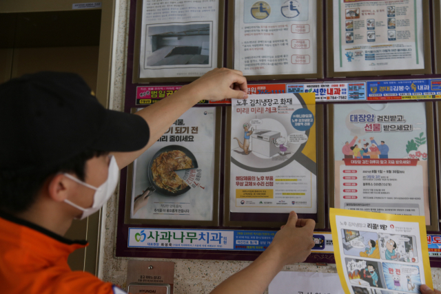 대구 수성소방서 직원이 노후 김치냉장고에 대한 자발적 리콜 안내문을 아파트에 부착하고 있다. 대구 수성소방서 제공.