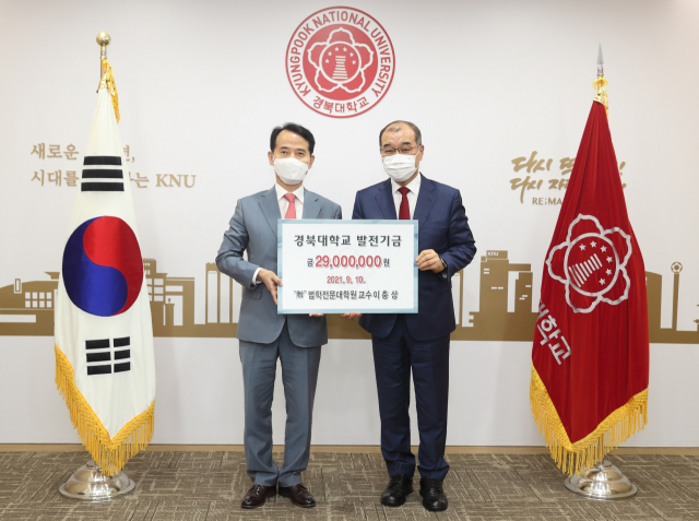이충상(왼쪽) 경북대 법학전문대학원 교수가 홍원화 총장에게 발전기금을 전달하고 있다. 경북대 제공