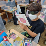 노인이해 교육에 참여한 대구 용지초등학교 학생이 노인유사복(안경)을 착용한 뒤 책 읽기 체험을 하는 모습. 대구시교육청 제공