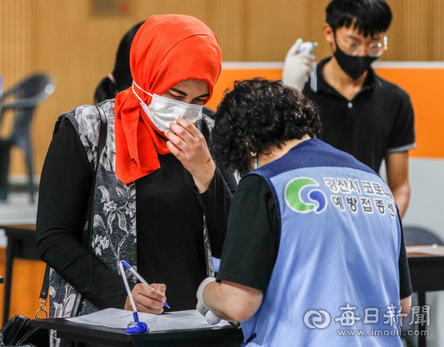 추석 연휴를 하루 앞둔 17일 오후 경산시 예방접종센터에서 한국어가 서툰 한 외국인이 접종센터 관계자의 도움을 받아 예진표를 작성하고 있다. 이날 0시 기준 경북 지역 코로나19 백신 1차 접종률은 인구대비 70.5%로, 도민 262만3천 여 명 가운데 183만 여 명이 1차 접종을 완료했다. 우태욱 기자 woo@imaeil.com
