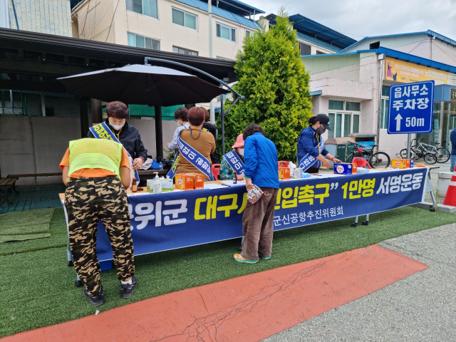 군위군민 두 명이 군위의 대구 편입을 촉구하는 서명운동에 동참하고 있다. 군위군통합신공항추진위원회 제공