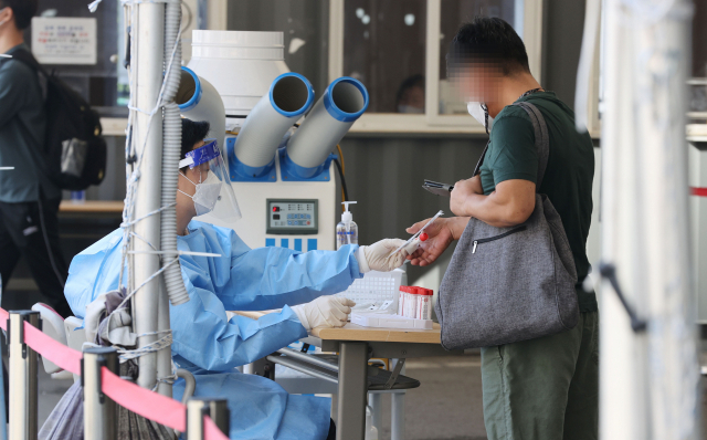 3일 서울역광장에 마련된 신종 코로나바이러스 감염증(코로나19) 임시 선별검사소에서 의료진이 검체 채취 키트를 건네고 있다. 연합뉴스