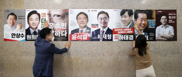 국민의힘 당직자가 지난달 24일 오후 서울 여의도 국회 본관 복도에 국민의힘 제20대 대통령선거 경선 예비 후보 포스터를 부착하고 있다. 연합뉴스