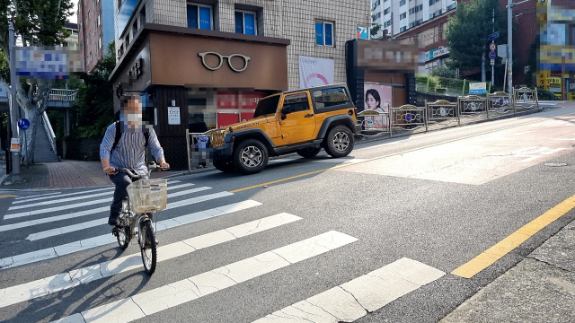 대구 동구 효목동의 교차로는 내리막길과 횡단보도가 맞닿아 있어 차량이나 보행자가 자전거와 부딪힐 사고 위험이 있다.