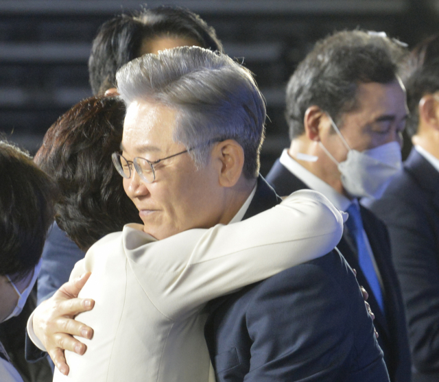 더불어민주당 제20대 대통령 후보에 선출된 이재명 경기도지사가 10일 오후 서울 송파구 올림픽공원 SK올림픽핸드볼경기장에서 열린 더불어민주당 서울 합동연설회에서 추미애 후보와 포옹하고 있다. 오른쪽 뒷편은 최종 2위로 고배를 마셨으며 경선 사퇴 후보 무효표 관련 이의를 제기한 상황인 이낙연 전 더불어민주당 대표. 연합뉴스