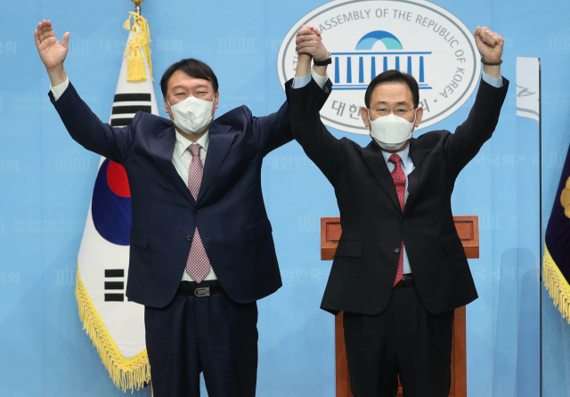 국민의힘 윤석열 대선 경선 후보(왼쪽)와 선거대책위원장으로 합류한 주호영 의원이 17일 오전 서울 여의도 국회 소통관에서 공동 기자회견을 가진 후 손을 맞잡아 들어 인사하고 있다. 연합뉴스