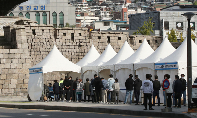 지난 18일 오전 서울 종로구 흥인지문 옆에 설치된 찾아가는 선별검사소에서 코로나19 집단감염이 발생한 동대문 인근 시장 종사자들이 검사를 받기 위해 대기하고 있다. 연합뉴스