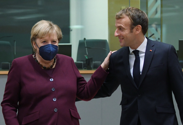 유럽연합(EU) 정상회의 둘째 날인 22일(현지시간) 벨기에 브뤼셀의 유럽의회에서 앙겔라 메르켈(왼쪽) 독일 총리와 에마뉘엘 마크롱(오른쪽) 프랑스 대통령이 다정히 어깨 위에 손을 얹고 담소하고 있다. EU 정상들은 이틀 일정으로 신종 코로나바이러스 감염증(코로나19) 사태와 에너지 가격 급등, 이민 문제 등을 논의한 뒤 이날 회의를 마쳤다. 연합뉴스