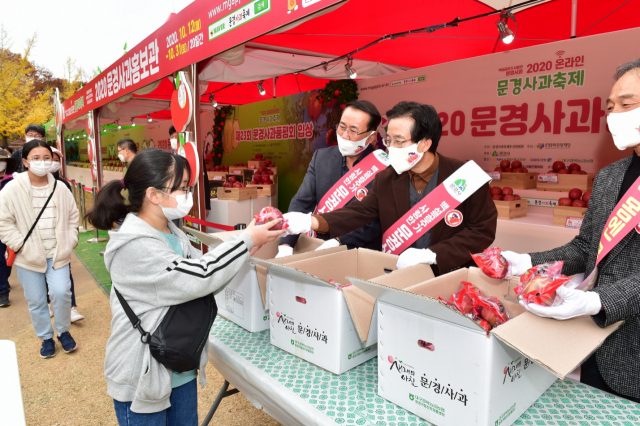 고윤환 문경시장(가운데)이 문경새재를 찾은 한 관광객에게 사과축제 홍보를 위한 시식용 사과를 건네고 있다. 문경시 제공