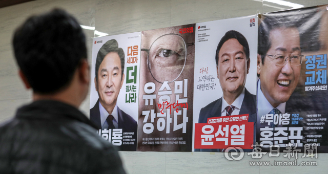 국민의힘 대선후보 선출을 하루 앞둔 4일 국민의힘 대구시당에 붙은 후보자 4명의 포스터를 시당 관계자가 바라보고 있다. 국민의힘은 