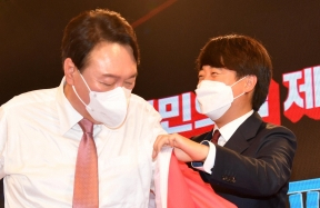 국민의힘 이준석 대표가 5일 서울 용산구 효창동 백범김구기념관에서 열린 제2차 전당대회에서 대선후보로 선출된 윤석열 후보에게 당 점퍼를 입혀주고 있다. 연합뉴스