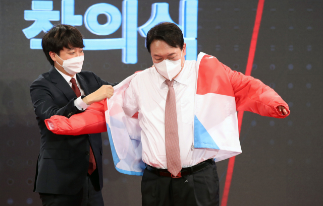 국민의힘 이준석 대표가 5일 서울 용산구 효창동 백범김구기념관에서 열린 제2차 전당대회에서 대선후보로 선출된 윤석열 후보에게 당 점퍼를 입혀주고 있다. 연합뉴스