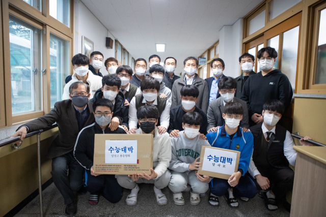 대구 달성고 출신 선배들이 수능시험을 앞둔 고3 후배들을 위해 선물한 사과와 떡을 들고 기념촬영을 하고 있다. 달성고 제공