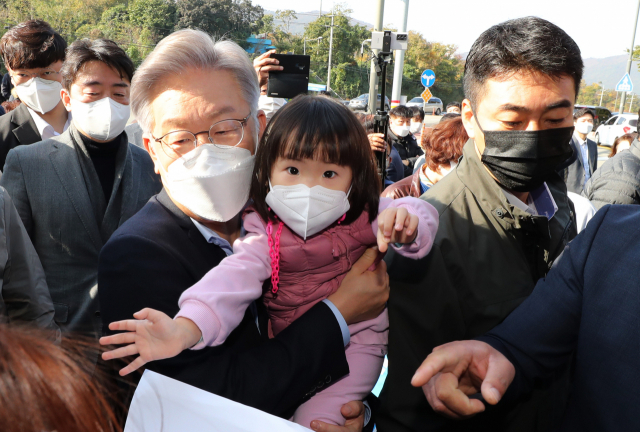더불어민주당 이재명 대선후보가 14일 경남 거제시 대우조선소 정문 앞에서 열린 대우조선소 노조·시민대책위 타운홀 미팅을 마친 뒤 대우조선해양으로 들어가던 중 어린아이를 안아주고 있다. 연합뉴스