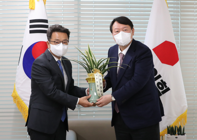국민의힘 윤석열 대선 후보가 15일 오후 서울 영등포 국민의힘 당사에서 이철희 청와대 정무수석으로부터 문재인 대통령의 축하 난을 전달받고 있다. 연합뉴스