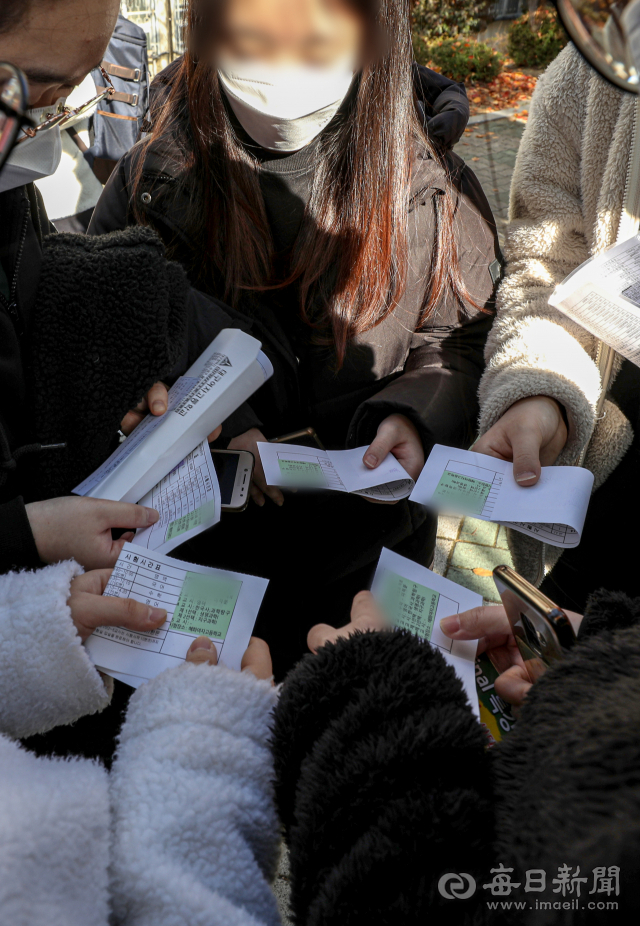 2022학년도 대학수학능력시험 예비소집일인 17일 오후 대구여자고등학교에서 수험생들이 수험표를 수령한 뒤 확인하고 있다. 안성완 기자 asw0727@imaeil.com