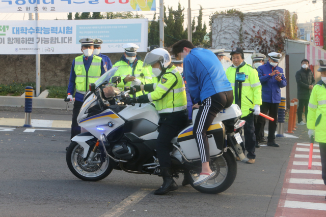 대학수학능력시험(수능)일인 18일 제주도교육청 제주95지구 제3시험장인 오현고등학교 정문 앞에서 한 수험생이 경찰 오토바이를 타고 온 후 내리고 있다. 연합뉴스