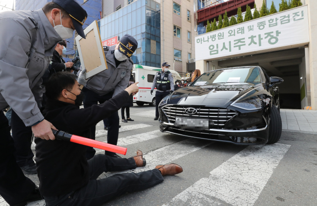 코로나19백신피해자가족협의회(코백회) 회원들이 19일 충북 예방접종 위탁의료기관인 청주시 하나병원 앞에서 정은경 질병관리청장의 차량을 막고 면담을 요구하고 있다. 연합뉴스