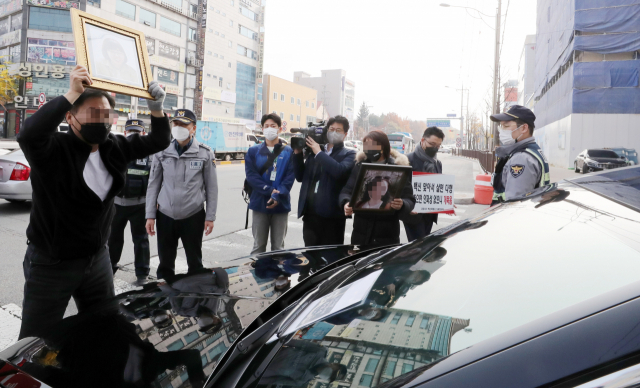 코로나19백신피해자가족협의회(코백회) 회원들이 19일 충북 예방접종 위탁의료기관인 청주시 하나병원 앞에서 정은경 질병관리청장의 차량을 막고 면담을 요구하고 있다. 연합뉴스
