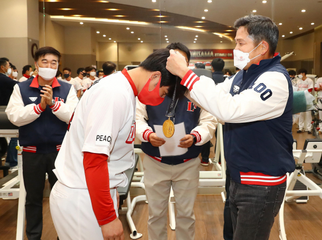 SSG랜더스 구단주인 정용진 신세계 그룹 부회장이 지난달 27일 선수단 클럽하우스를 찾아 400홈런 기록을 세운 최정에게 순금 60돈으로 만든 기념 메달을 걸어주고 있다. 연합뉴스