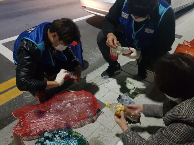 남구청 공무원이 동네에 배출된 투명 페트병을 다시 바닥에 풀어 손수 라벨을 제거하고 있다. 남구청 제공