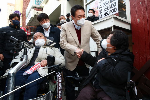 국민의힘 윤석열 대선후보(가운데)와 이준석 대표(왼쪽)가 8일 오후 서울 종로구 대학로 거리 플렛폼74에서 열린 청년문화예술인간담회에 참석하기 전 입구에서 윤 후보와 면담을 요구하던 장애인 단체 회원과 대화하고 있다. 연합뉴스