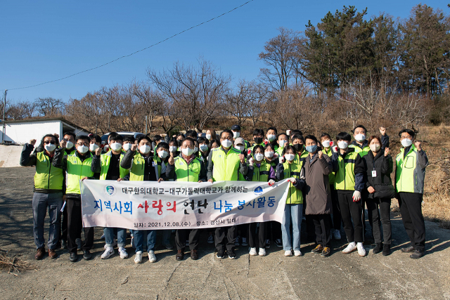 대구한의대, 대구가톨릭대 총장과 교직원, 학생들이 연탄나눔 봉사활동을 실시한 뒤 파이팅을 외치고 있다. 대구한의대 제공